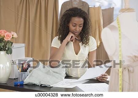 Seamstress reading paperwork at shop View Large Photo Image Stock Photo - Seamstress reading paperwork at shop. Fotosearch