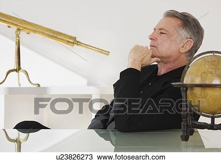Stock Image - Senior businessman next to globe and telescope. Fotosearch
