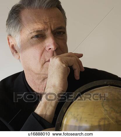 Stock Image - Senior businessman next to globe. Fotosearch