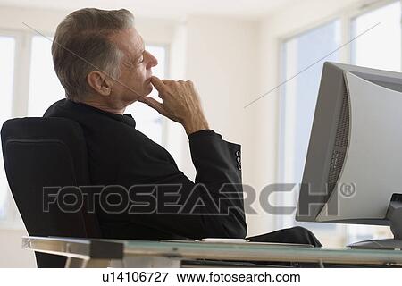 Stock Photo - Senior businessman sitting at desk. Fotosearch