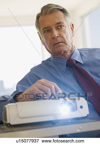 Senior businessman using projector in conference room View Large Photo Image Stock Photo - Senior businessman using projector in conference room. Fotosearch