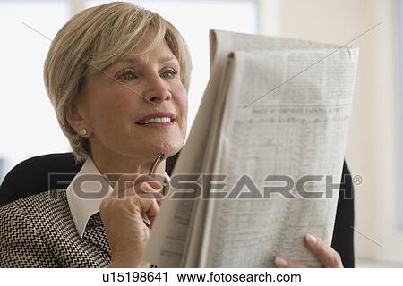 Stock Image - Senior businesswoman reading newspaper. Fotosearch