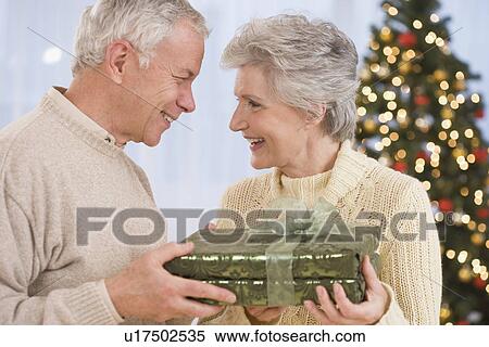 Senior couple holding Christmas gift View Large Photo Image Stock Photography - Senior couple holding Christmas gift. Fotosearch