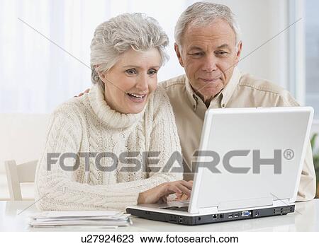 Senior couple looking at laptop View Large Photo Image Stock Image - Senior couple looking at laptop. Fotosearch