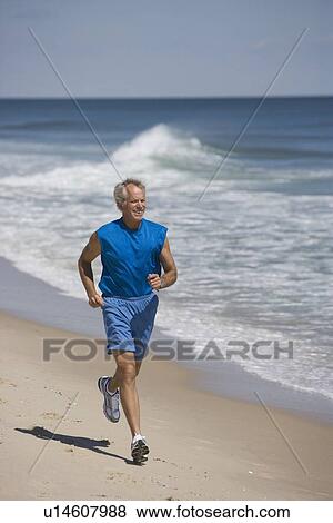 Stock Photo - Senior man jogging on beach. Fotosearch