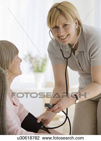 Stock Image - Senior woman having blood pressure taken. Fotosearch