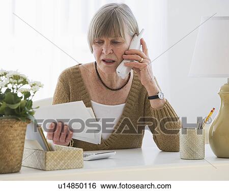 Stock Photograph - Senior woman looking at bills. Fotosearch
