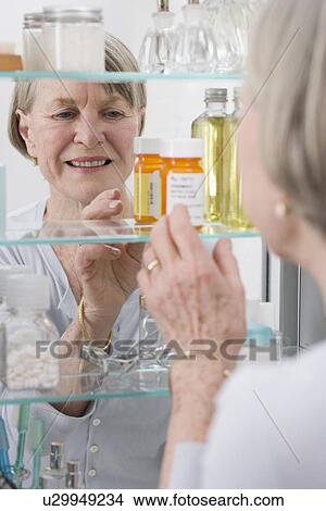 Picture - Senior woman looking in medicine cabinet. Fotosearch