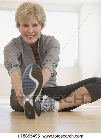 Stock Photography - Senior woman stretching on floor. Fotosearch