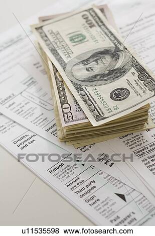 Stock Photo - Stack of money on tax forms. Fotosearch