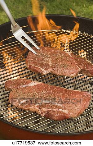 Stock Photo - Steaks cooking on grill. Fotosearch