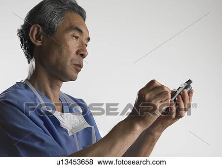 Stock Photo - Studio shot of male doctor using PDA. Fotosearch
