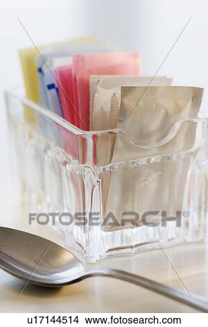 Picture - Sugar and sweetener packets next to spoon. Fotosearch
