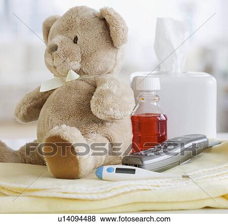 Stock Photo - Teddy bear, medication, thermometer and telephone on blanket. Fotosearch