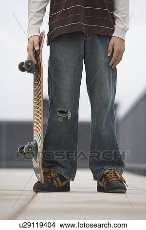 Picture - Teenaged boy holding skateboard. Fotosearch