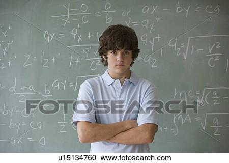 Stock Image - Teenaged boy in front of blackboard with math equations. Fotosearch