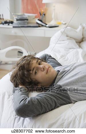 Teenaged boy laying on bed View Large Photo Image Stock Image - Teenaged boy laying on bed. Fotosearch