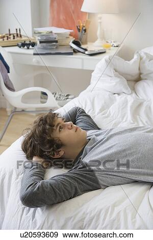 Teenaged boy laying on bed View Large Photo Image Stock Photo - Teenaged boy laying on bed. Fotosearch