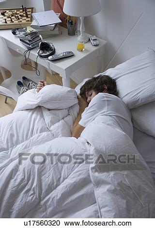 Stock Image - Teenaged boy sleeping in bed. Fotosearch