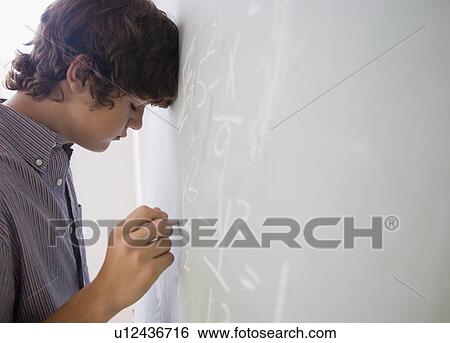 Teenaged boy writing math equations on blackboard View Large Photo Image Stock Photograph - Teenaged boy writing math equations on blackboard. Fotosearch