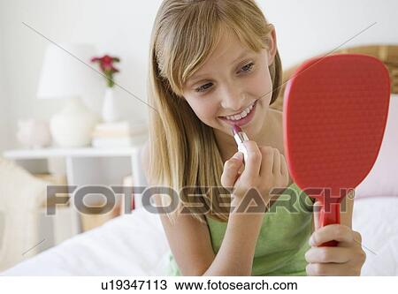 Stock Image - Teenaged girl applying lipstick. Fotosearch