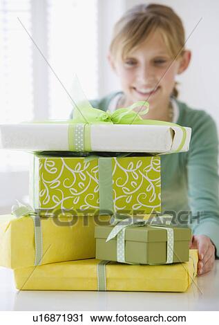 Stock Image - Teenaged girl behind stack of gifts. Fotosearch
