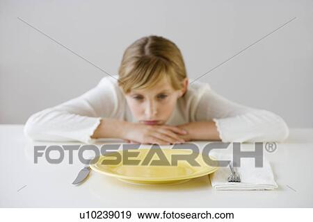 Stock Photo - Teenaged girl looking at empty plate. Fotosearch