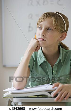Stock Image - Teenaged girl thinking at school desk. Fotosearch