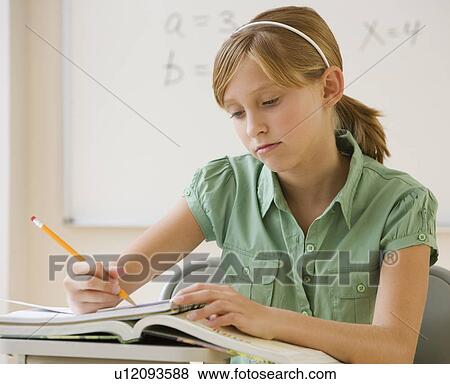 Stock Photo - Teenaged girl writing at school desk. Fotosearch