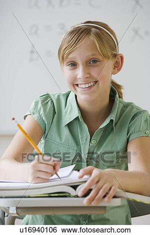 Teenaged girl writing at school desk View Large Photo Image Stock Photograph - Teenaged girl writing at school desk. Fotosearch