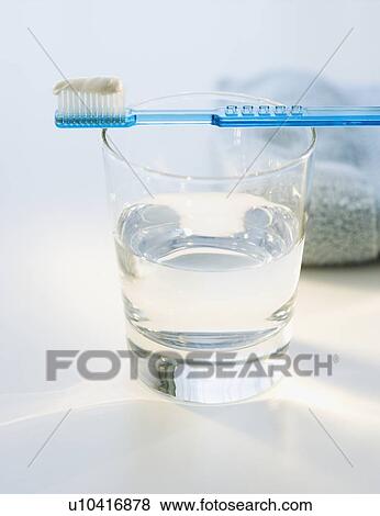Stock Photo - Toothbrush with toothpaste on glass of water. Fotosearch