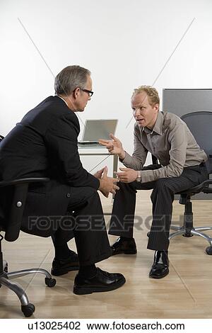 Two businessmen sitting and talking View Large Photo Image Stock Image - Two businessmen sitting and talking. Fotosearch