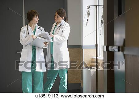 Stock Image - Two female doctors discussing chart. Fotosearch