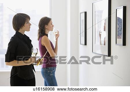 Stock Photo - Two women looking at artwork in gallery. Fotosearch