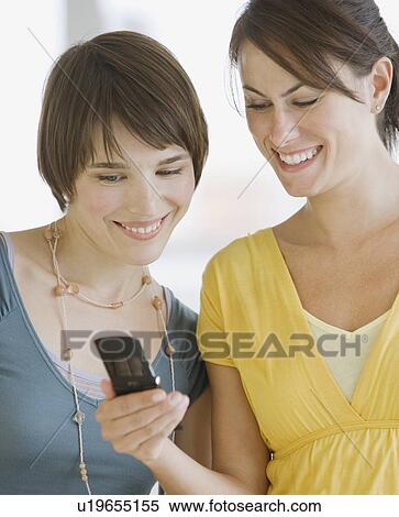 Two women looking at cell phone View Large Photo Image Stock Photography - Two women looking at cell phone. Fotosearch