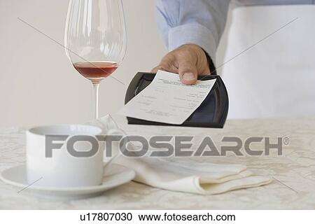 Stock Image - Waiter leaving check on table. Fotosearch