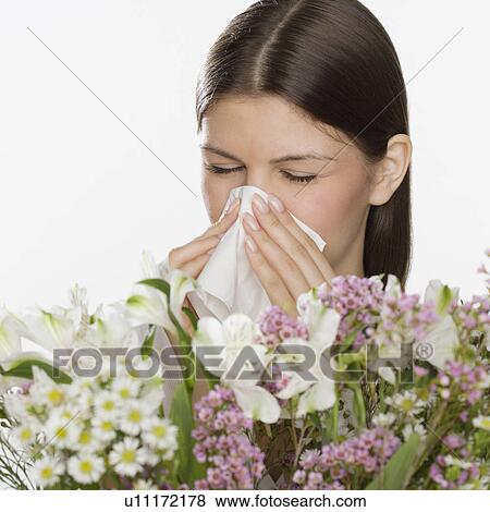 Stock Photo - Woman blowing nose next to flowers. Fotosearch