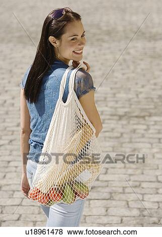 Stock Photo - Woman carrying mesh bag of groceries. Fotosearch