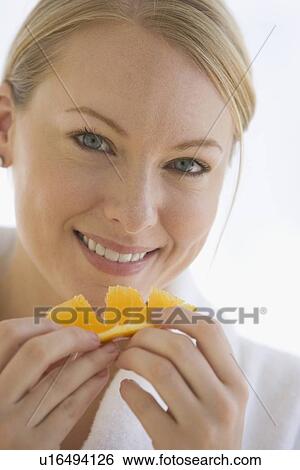 Stock Photograph - Woman eating orange wedge. Fotosearch