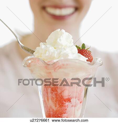 Stock Image - Woman eating strawberry parfait. Fotosearch