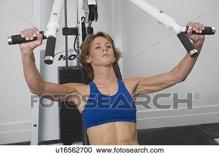 Stock Image - Woman exercising at gym. Fotosearch