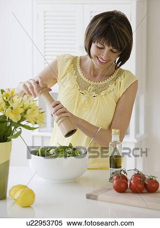 Stock Photography - Woman grinding pepper onto salad. Fotosearch