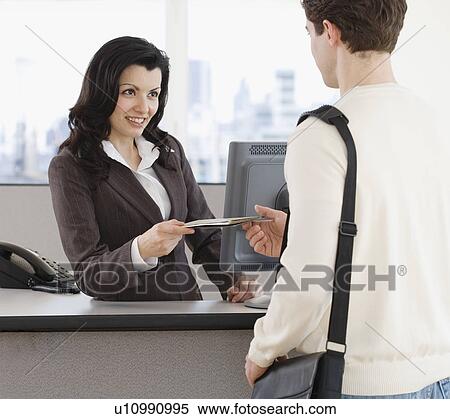 Stock Photography - Woman handing paperwork over counter to man. Fotosearch