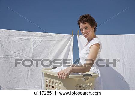 Stock Image - Woman hanging laundry on clothes line. Fotosearch