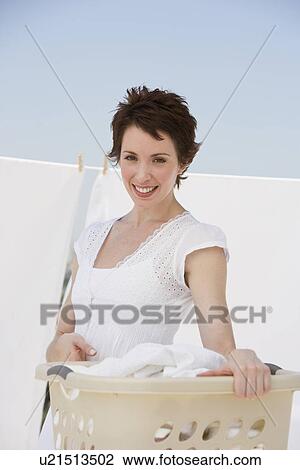 Stock Image - Woman hanging laundry on clothes line. Fotosearch