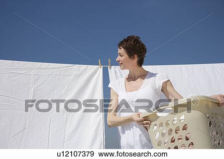 Stock Photo - Woman hanging laundry on clothes line. Fotosearch