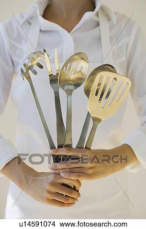 Woman holding assorted serving utensils View Large Photo Image Picture - Woman holding assorted serving utensils. Fotosearch