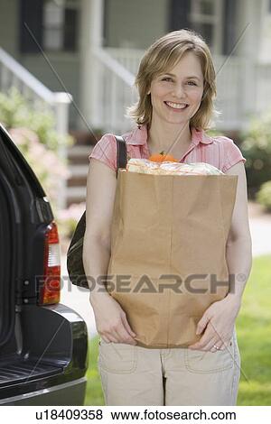 Stock Photo - Woman holding bag of groceries. Fotosearch