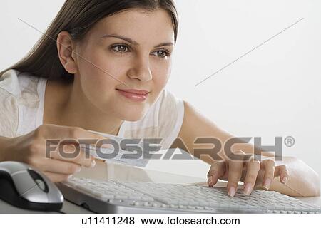 Woman holding credit card and using computer keyboard View Large Photo Image Stock Photo - Woman holding credit card and using computer keyboard. Fotosearch
