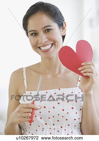 Stock Image - Woman holding cut out paper heart. Fotosearch